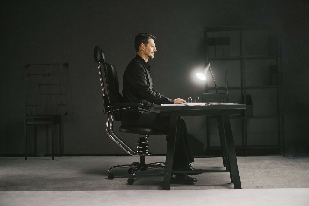 Pisarniški stol pilot v črni barvi slika moškega v pisarni