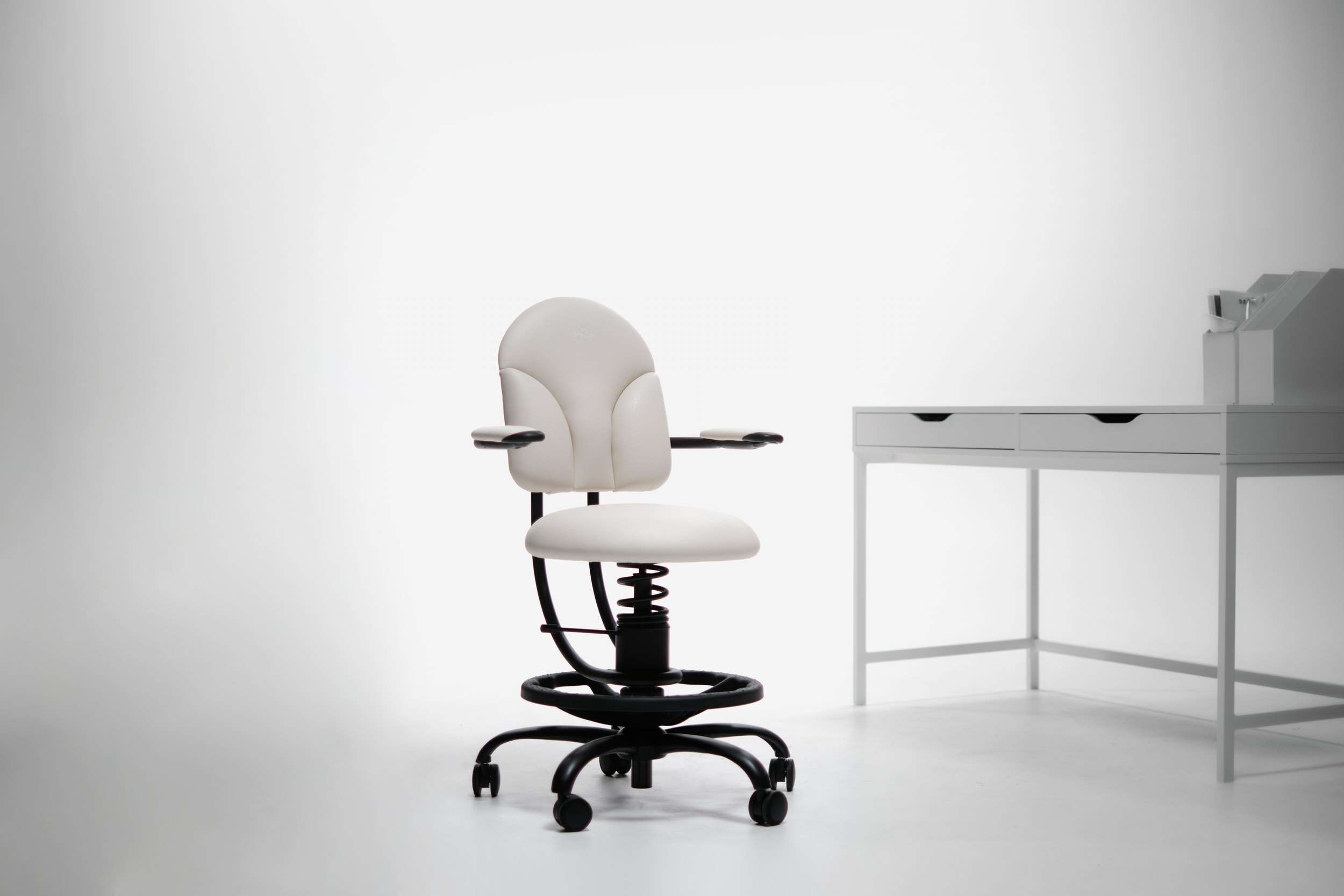 Pisalni stol basic v beli barvi poleg pisalne mize